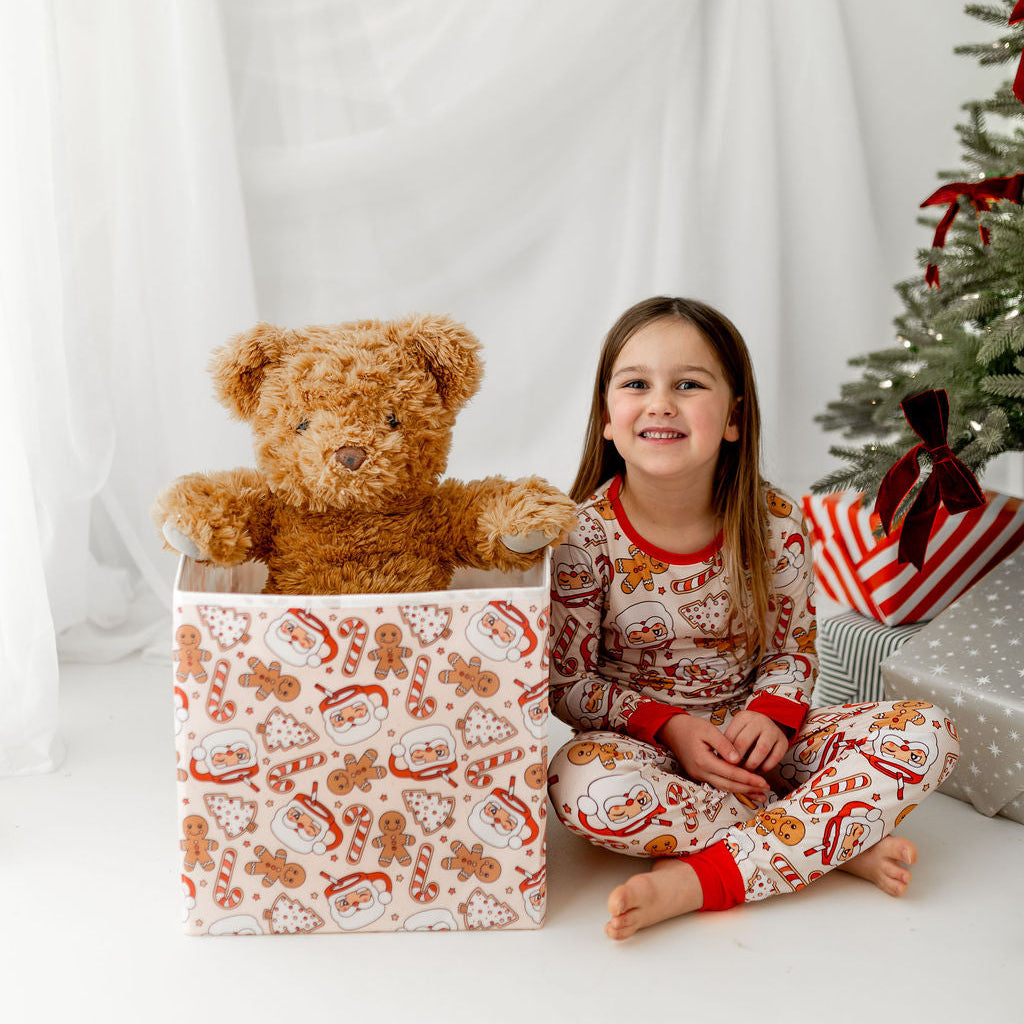 Child in pajamas with a teddy bear and Christmas decorations